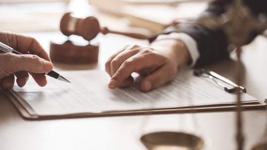 Attorney showing client where to sign on legal document